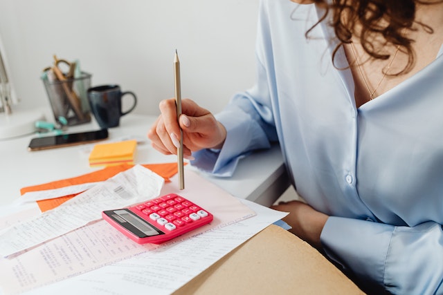 woman sitting in front of documents with calculator