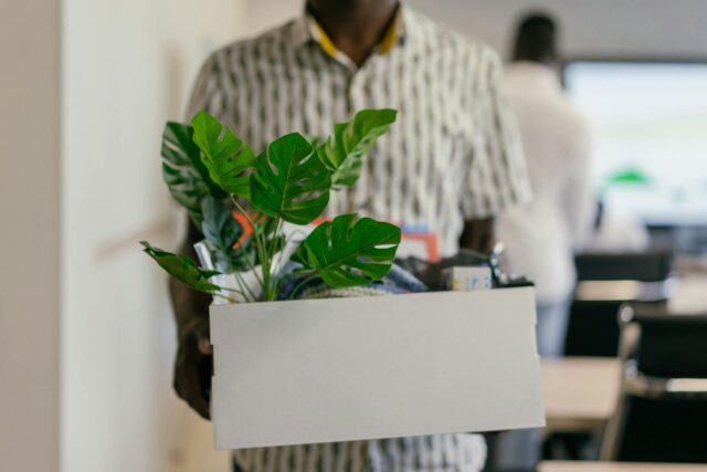 man holding box of personal belongings from workplace