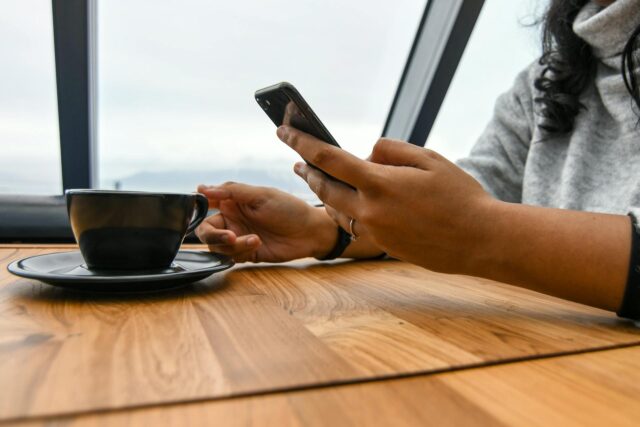 woman holding phone while having coffee